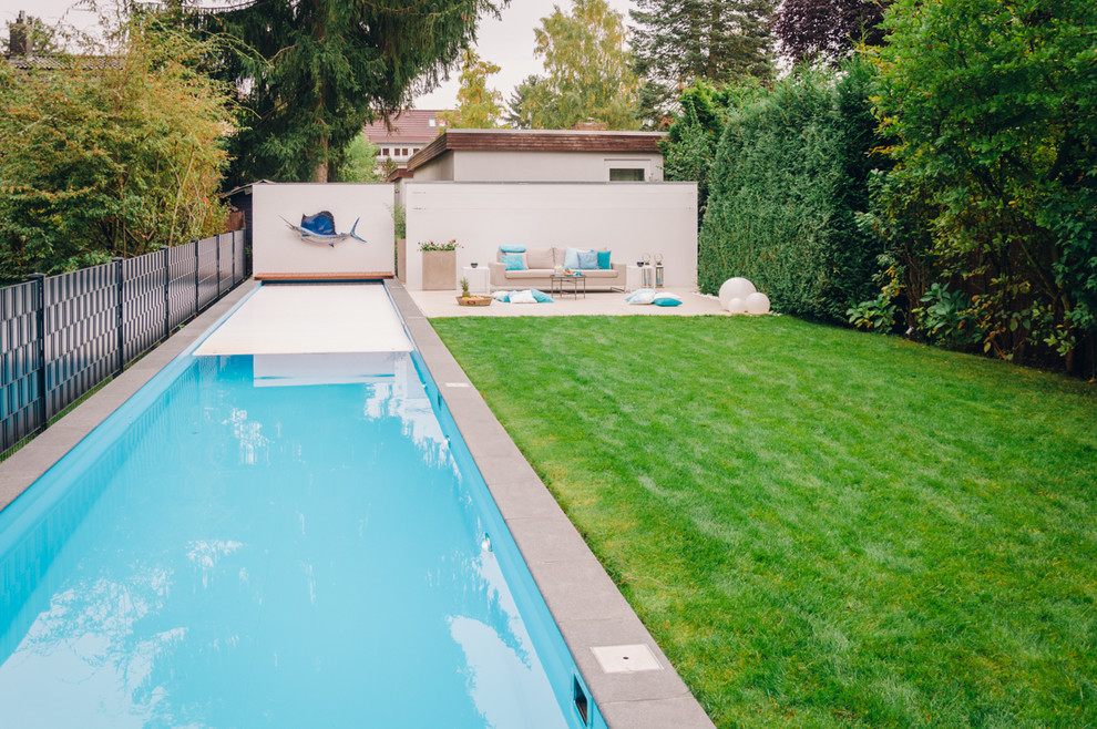 Immagine di una grande piscina monocorsia minimal rettangolare nel cortile laterale con pavimentazioni in pietra naturale