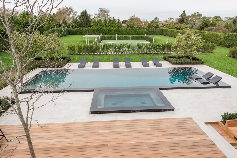 Пример оригинального дизайна: огромный бассейн-инфинити произвольной формы на заднем дворе в современном стиле с домиком у бассейна и покрытием из плитки
