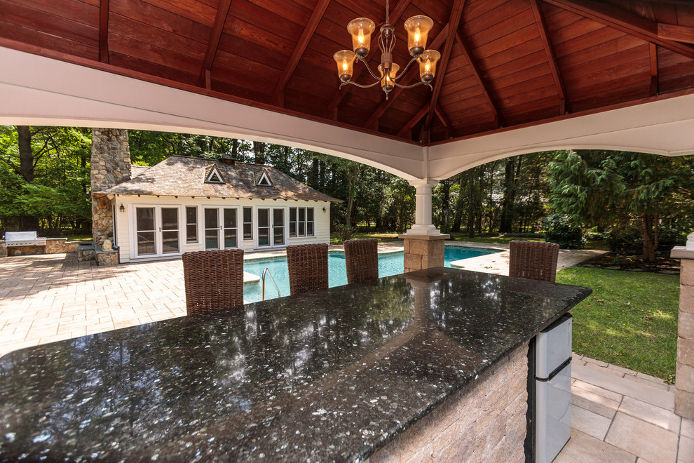 На фото: большой бассейн произвольной формы на заднем дворе в классическом стиле с домиком у бассейна и покрытием из каменной брусчатки