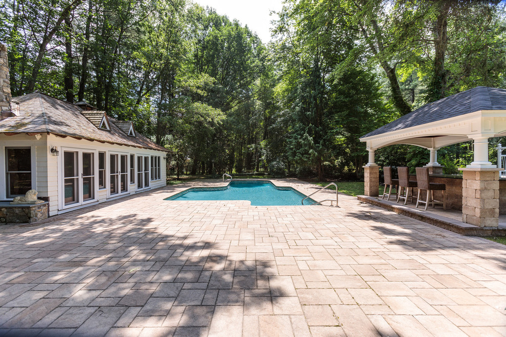 На фото: большой бассейн произвольной формы на заднем дворе в классическом стиле с домиком у бассейна и покрытием из каменной брусчатки