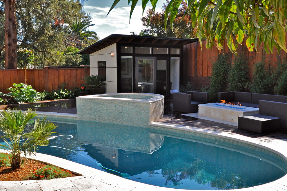 Réalisation d'une piscine arrière design en forme de haricot avec du carrelage et un bain bouillonnant.