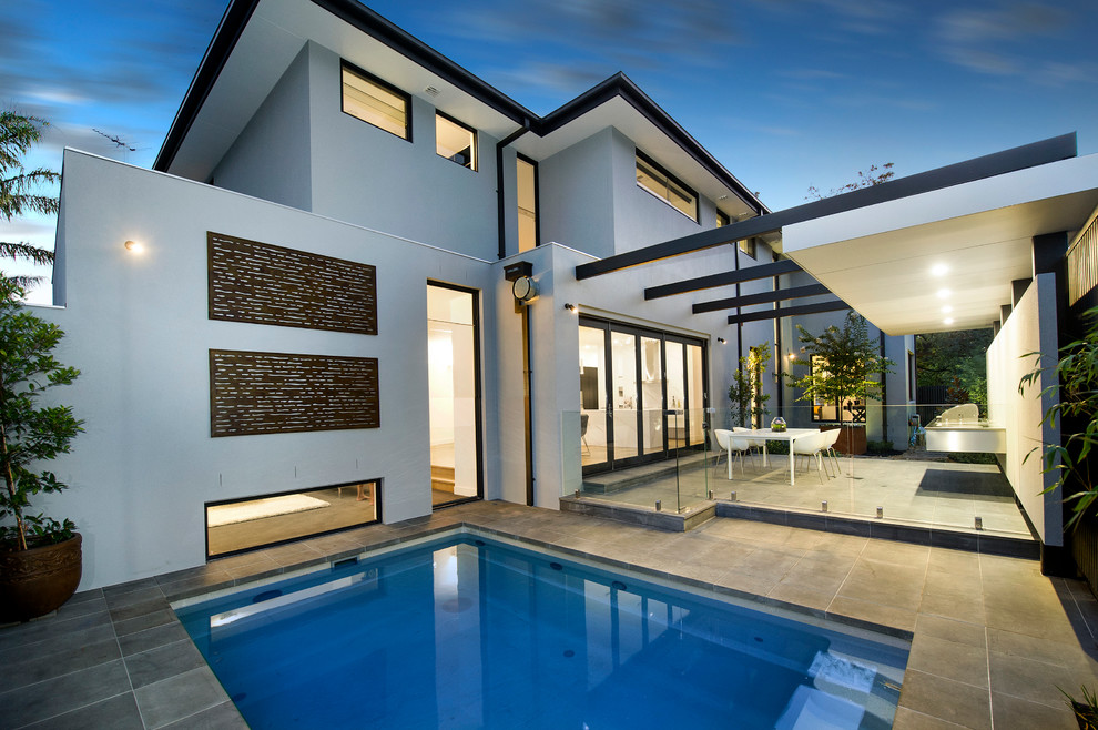 Imagen de piscina actual de tamaño medio rectangular en patio trasero con losas de hormigón