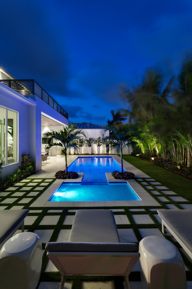 Ejemplo de piscina natural moderna de tamaño medio rectangular en patio trasero con adoquines de hormigón