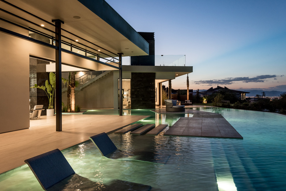 Foto de piscinas y jacuzzis infinitos contemporáneos extra grandes a medida en patio trasero con adoquines de hormigón