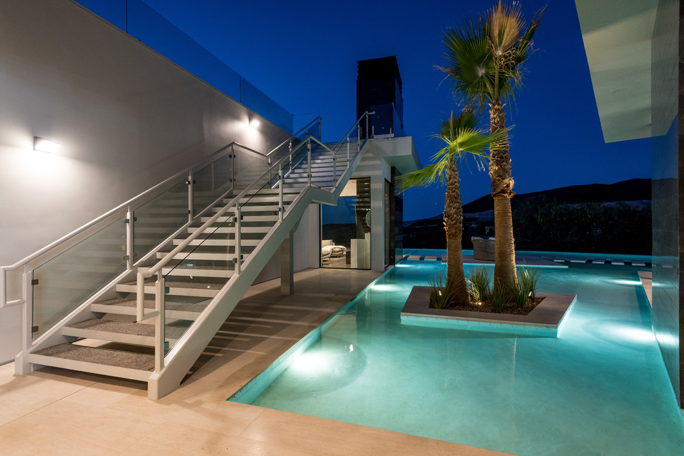 Esempio di un'ampia piscina a sfioro infinito contemporanea personalizzata dietro casa con una vasca idromassaggio e pavimentazioni in cemento