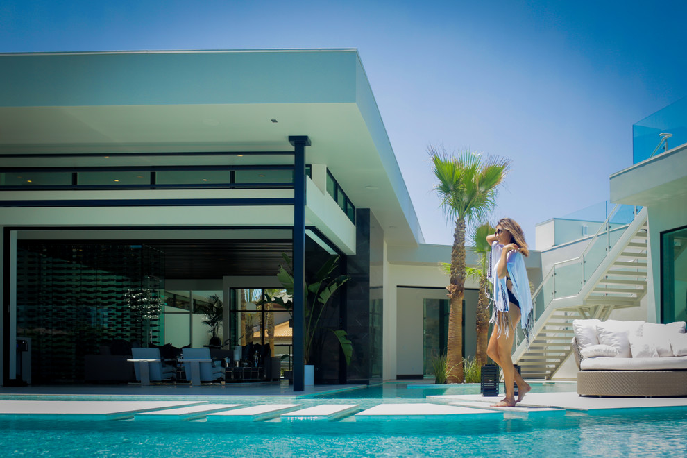 Diseño de piscinas y jacuzzis infinitos contemporáneos extra grandes a medida en patio trasero con adoquines de hormigón