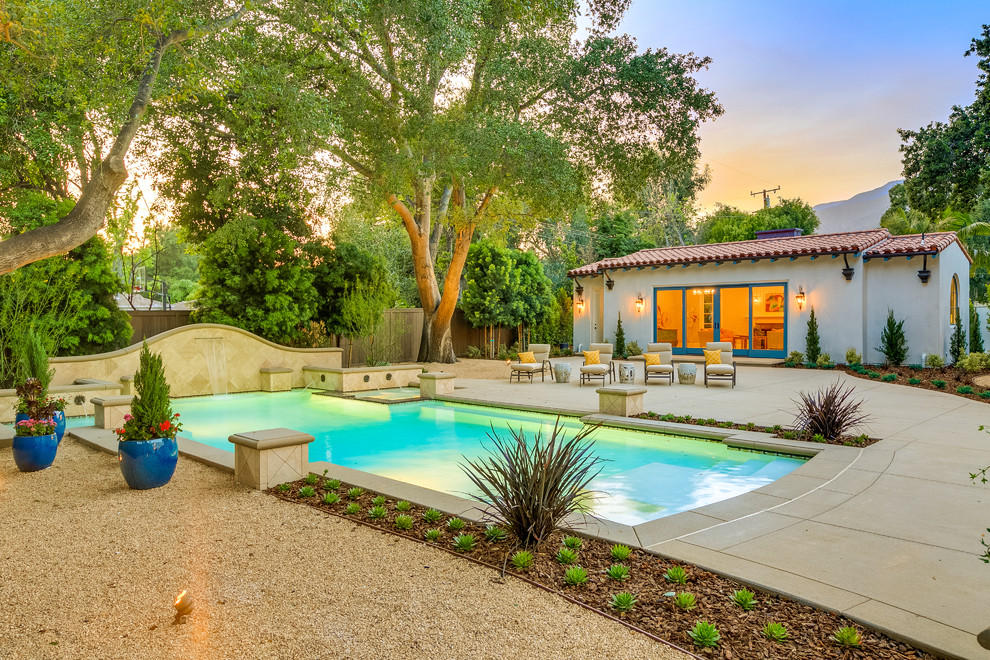Modelo de casa de la piscina y piscina alargada mediterránea grande rectangular en patio trasero con losas de hormigón