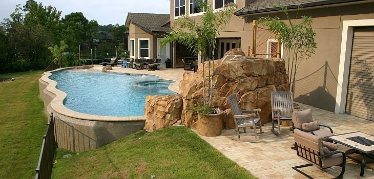 Foto de piscina con tobogán elevada costera grande a medida en patio trasero con suelo de baldosas