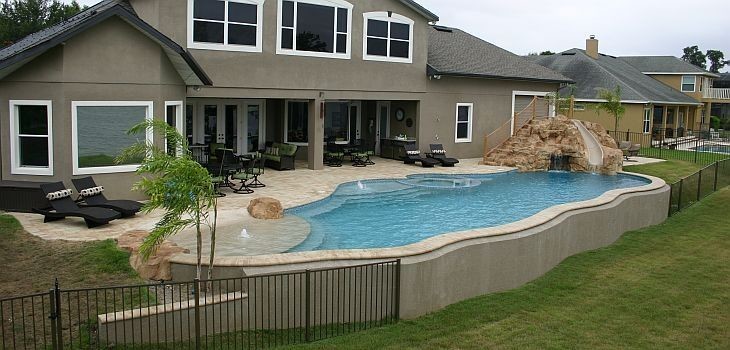 Photo of a large nautical back custom shaped natural swimming pool in Orlando with a water slide and concrete paving.
