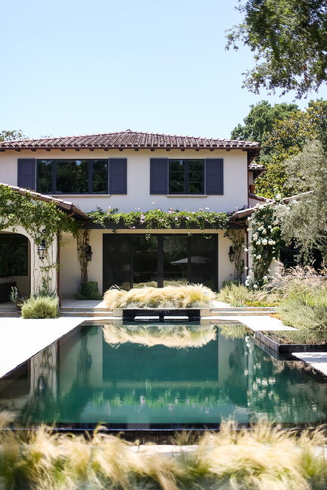 Großer Mediterraner Infinity-Pool hinter dem Haus in rechteckiger Form mit Natursteinplatten in Los Angeles