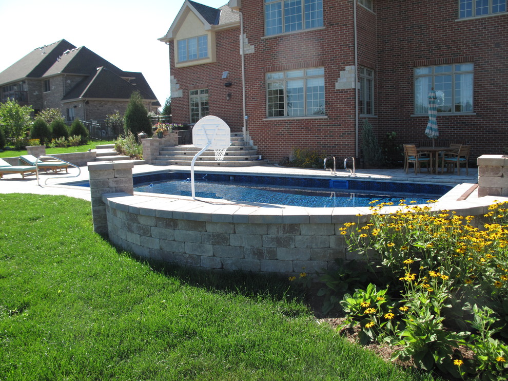 Modelo de piscina tradicional de tamaño medio rectangular en patio trasero con adoquines de ladrillo