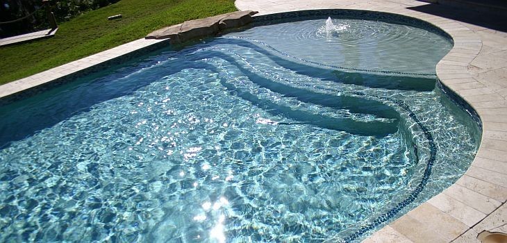 Ejemplo de piscina con tobogán costera de tamaño medio redondeada en patio trasero con adoquines de ladrillo