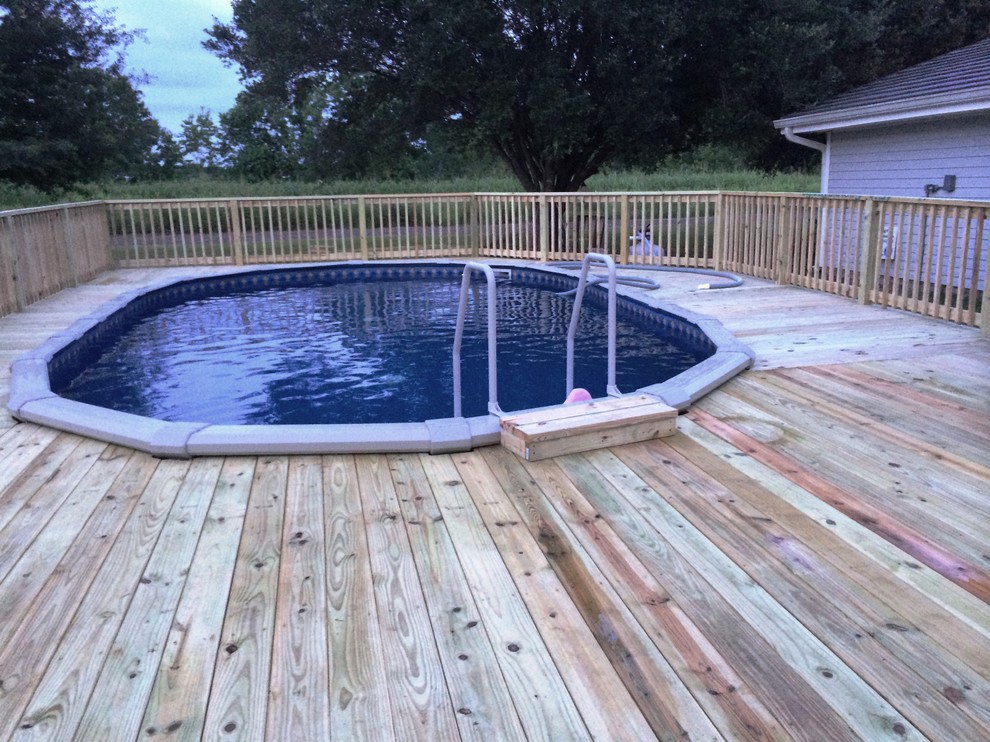 Exemple d'une piscine hors-sol et arrière chic de taille moyenne avec une terrasse en bois.
