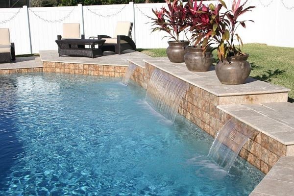 Idee per una grande piscina moderna personalizzata dietro casa con fontane e pavimentazioni in cemento