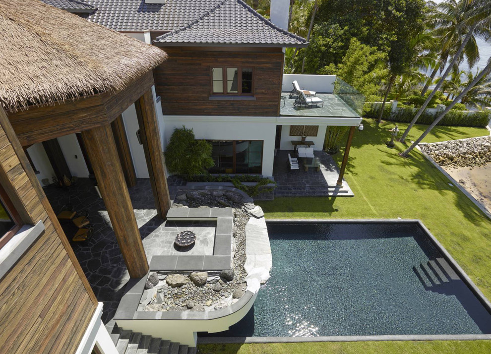 Esempio di un'ampia piscina monocorsia etnica rettangolare dietro casa con lastre di cemento