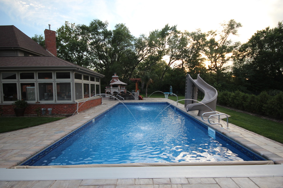 Idee per una grande piscina chic rettangolare dietro casa con pavimentazioni in mattoni e un acquascivolo