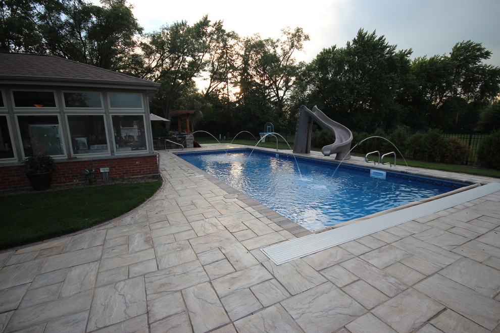 Exempel på en mycket stor klassisk rektangulär pool på baksidan av huset, med marksten i tegel