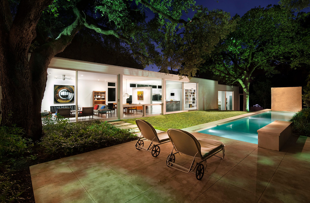 Ejemplo de piscina alargada contemporánea pequeña rectangular en patio trasero con adoquines de piedra natural