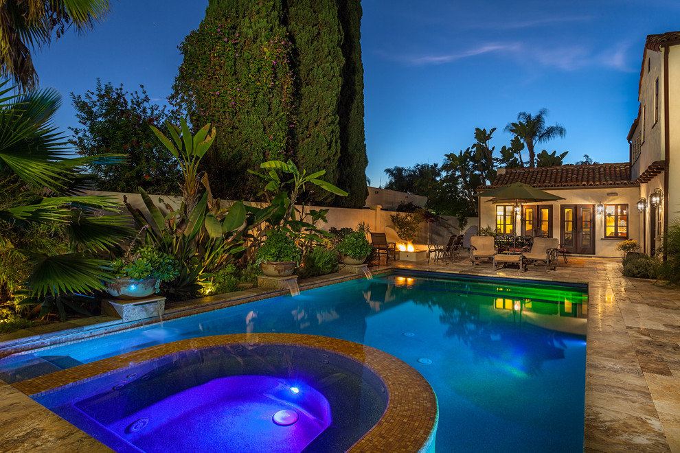 Ispirazione per una grande piscina monocorsia mediterranea rettangolare dietro casa con una vasca idromassaggio e pavimentazioni in pietra naturale