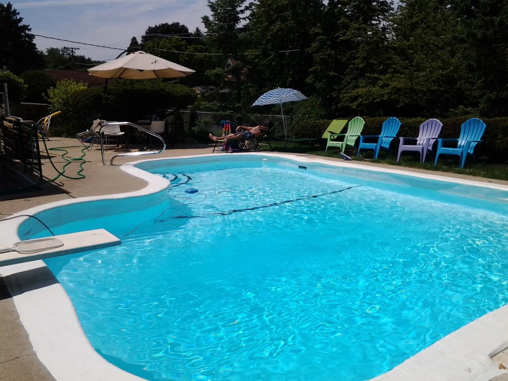 Immagine di una piscina boho chic a "C" di medie dimensioni e dietro casa con lastre di cemento