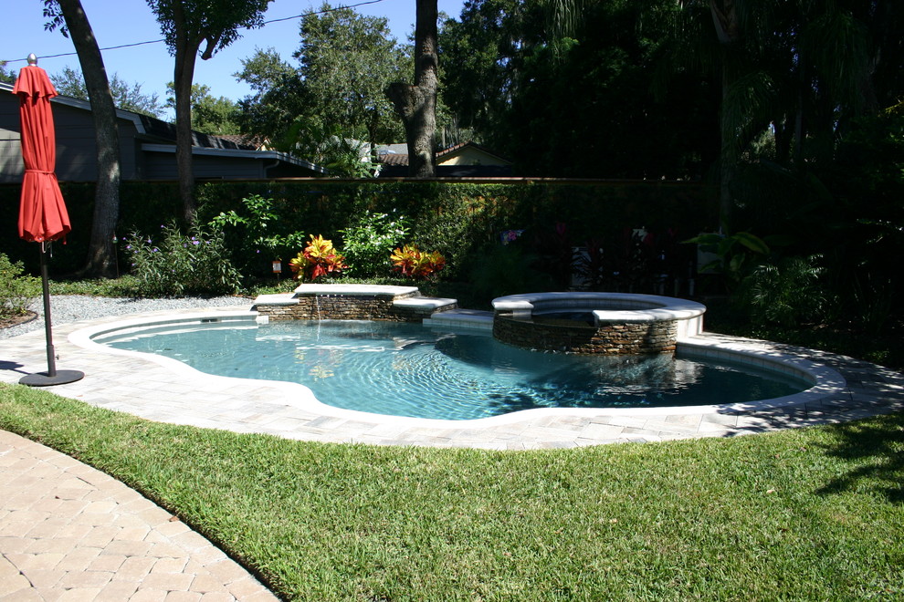 Стильный дизайн: бассейн среднего размера, произвольной формы на заднем дворе в морском стиле с джакузи и мощением тротуарной плиткой - последний тренд