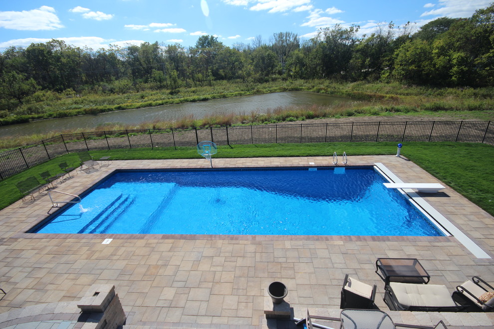 Inspiration for an expansive classic back rectangular swimming pool in Chicago with a water feature and brick paving.