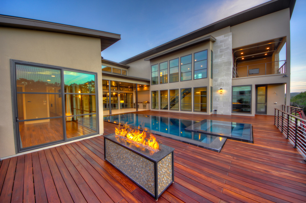 Aménagement d'une piscine à débordement contemporaine avec une cour et une terrasse en bois.