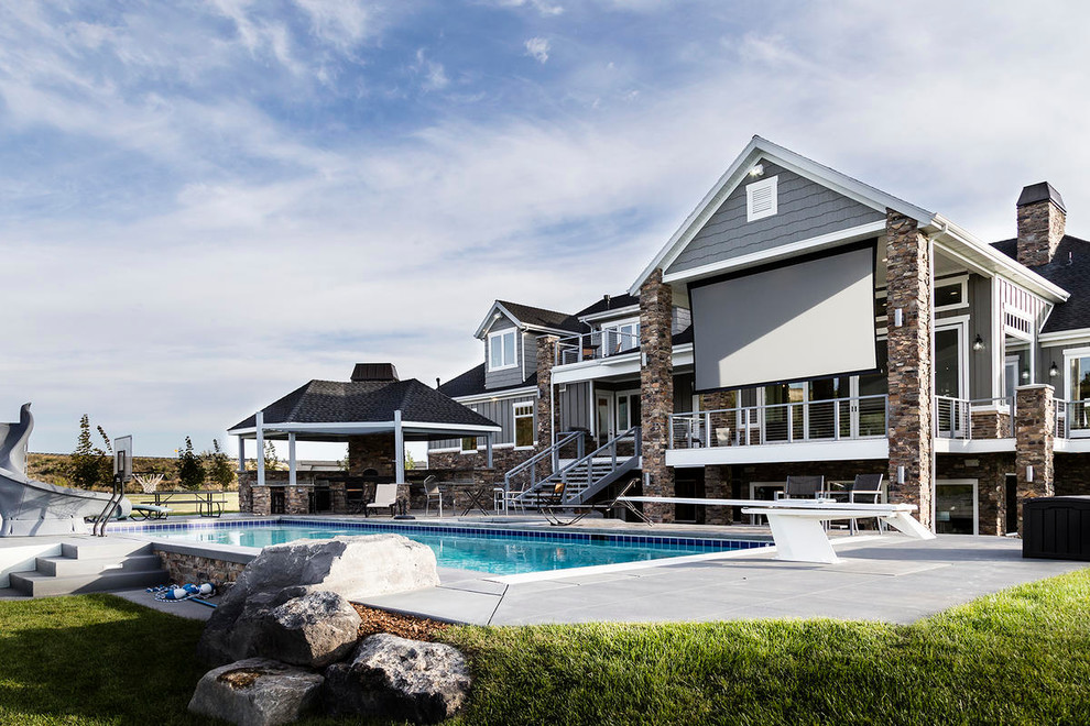 Foto di una grande piscina monocorsia stile americano rettangolare dietro casa con un acquascivolo e lastre di cemento