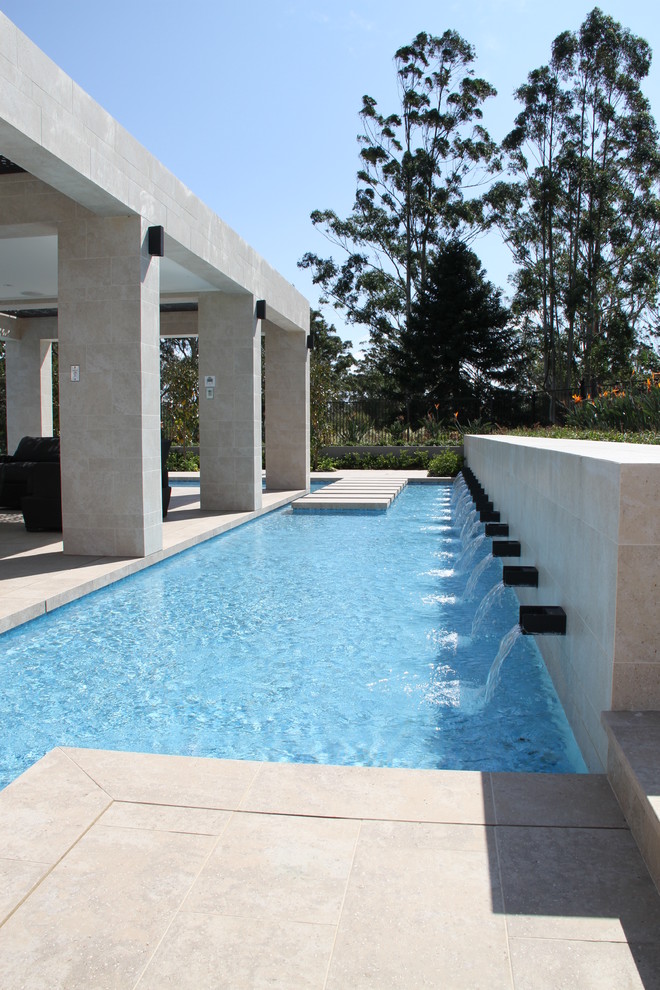 Foto di una grande piscina a sfioro infinito personalizzata dietro casa con una dépendance a bordo piscina e pavimentazioni in pietra naturale