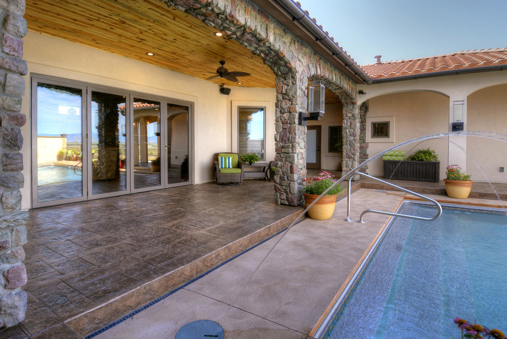Ejemplo de piscina con fuente mediterránea rectangular en patio con suelo de hormigón estampado