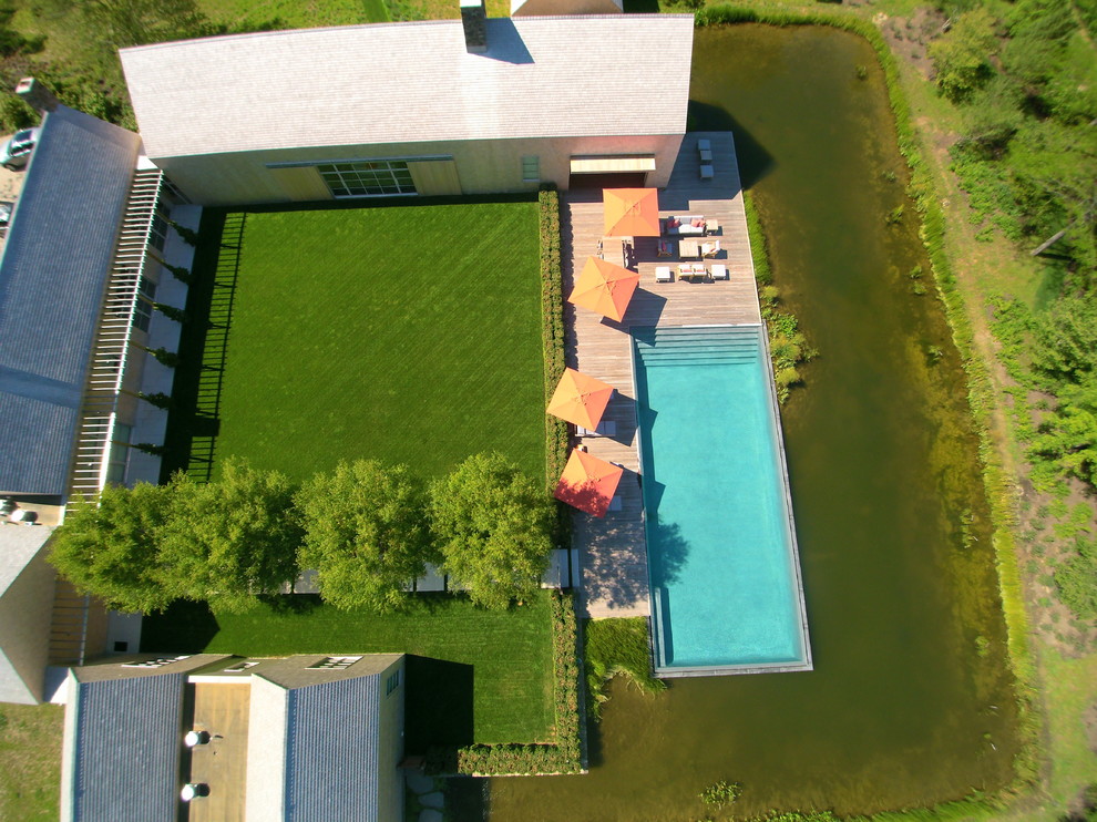 Diseño de piscina con fuente infinita rectangular en patio trasero con entablado