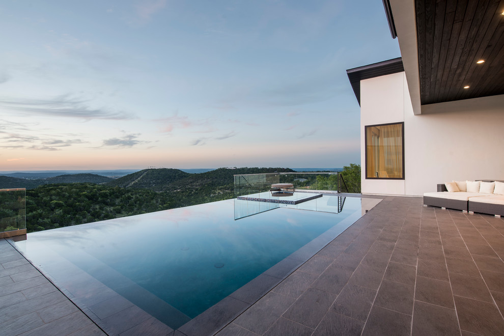 Foto di un'ampia piscina a sfioro infinito design rettangolare dietro casa con piastrelle