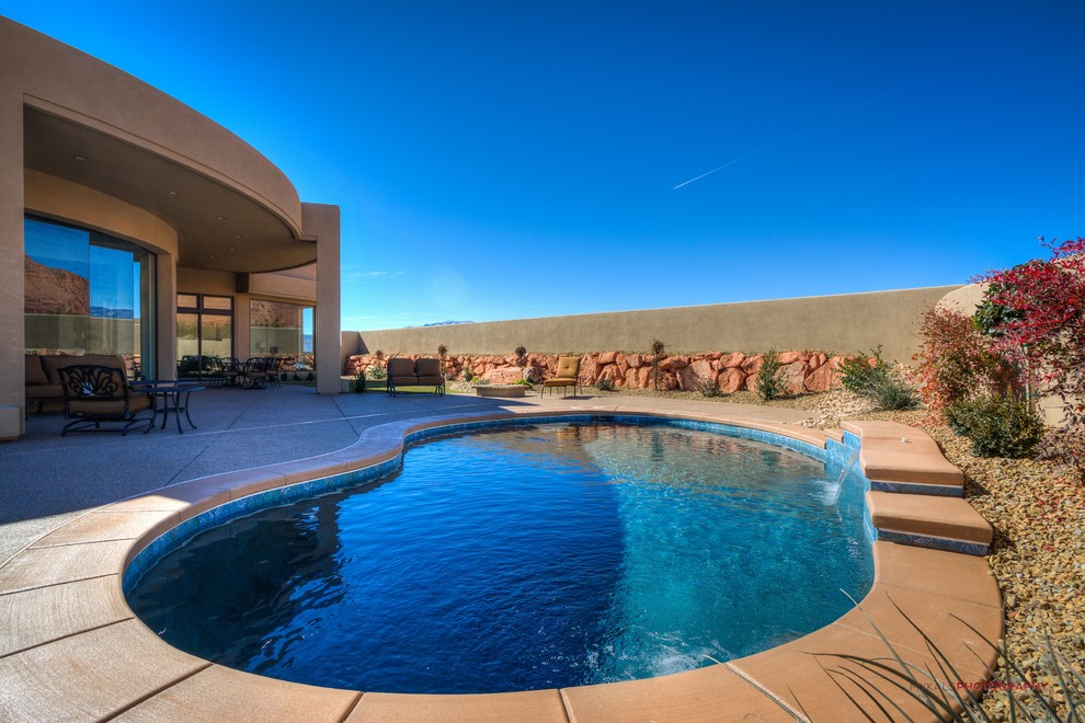 Ejemplo de piscina con fuente natural de estilo americano pequeña tipo riñón en patio trasero con gravilla