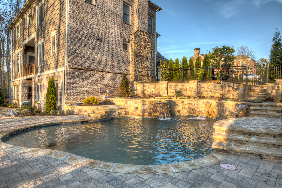Стильный дизайн: большой естественный бассейн произвольной формы на заднем дворе в викторианском стиле с фонтаном и настилом - последний тренд