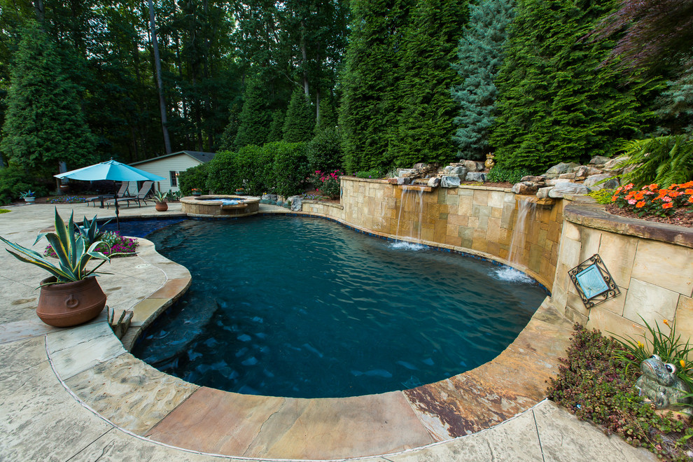Diseño de piscina con fuente natural tradicional grande a medida en patio trasero con suelo de hormigón estampado