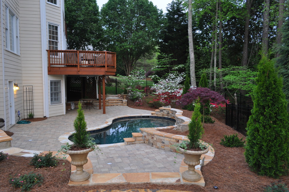 This is an example of a medium sized traditional back custom shaped swimming pool in Atlanta with brick paving.