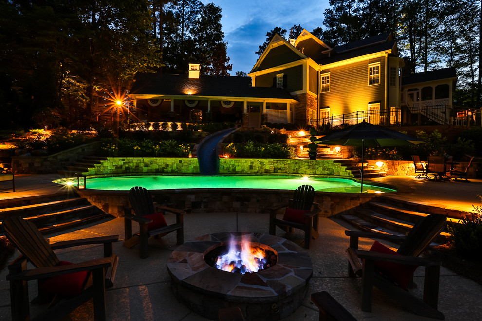 Immagine di una grande piscina naturale rustica personalizzata dietro casa con un acquascivolo e pedane