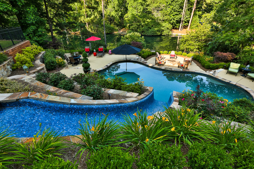 На фото: естественный бассейн среднего размера, произвольной формы на заднем дворе в современном стиле с водной горкой и настилом