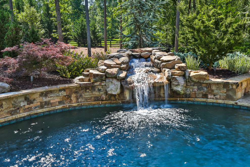 Small island style backyard stamped concrete and custom-shaped natural pool fountain photo in Atlanta