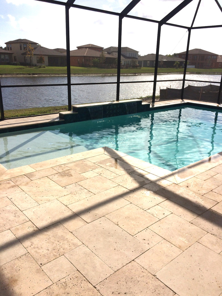 Medium sized classic back rectangular swimming pool in Tampa with a water feature and tiled flooring.