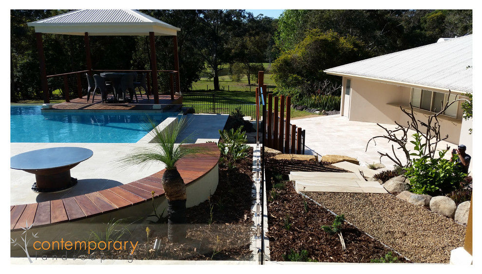 Réalisation d'une piscine naturelle et arrière design ronde avec une terrasse en bois.