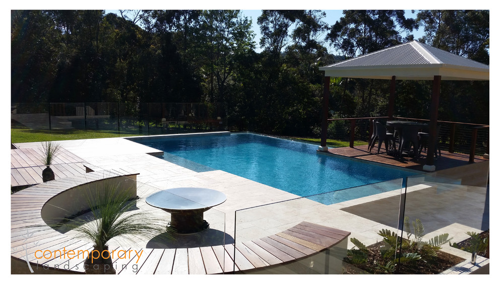 Cette image montre une piscine naturelle et arrière design ronde avec une terrasse en bois.