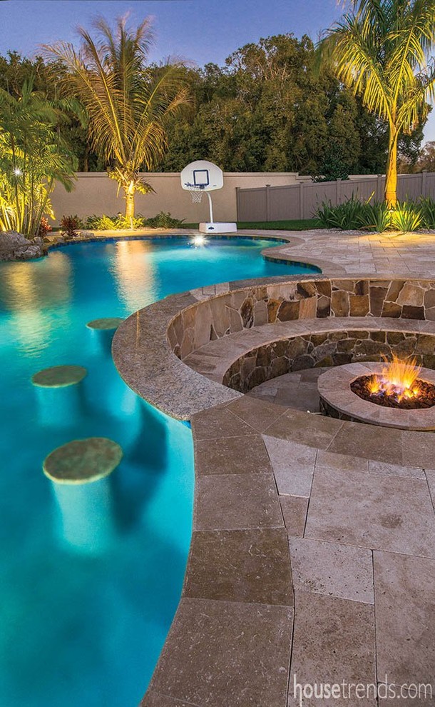 Immagine di un'ampia piscina naturale tropicale a "C" dietro casa con una vasca idromassaggio e pavimentazioni in pietra naturale