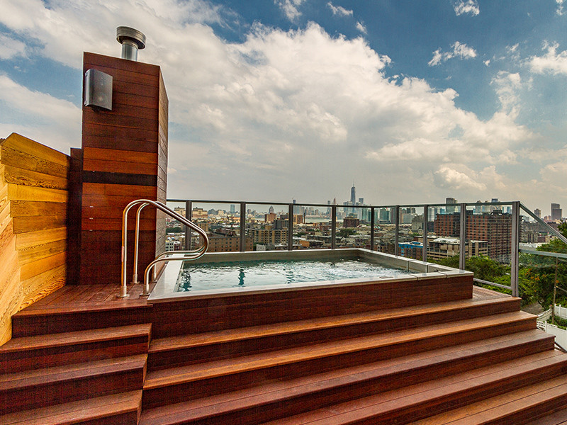 Aménagement d'une piscine sur toit industrielle rectangle avec un bain bouillonnant et une terrasse en bois.