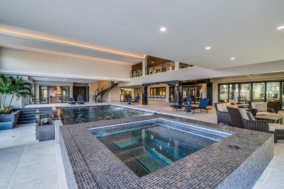 На фото: большой спортивный, прямоугольный бассейн в доме в стиле неоклассика (современная классика) с джакузи и покрытием из плитки с
