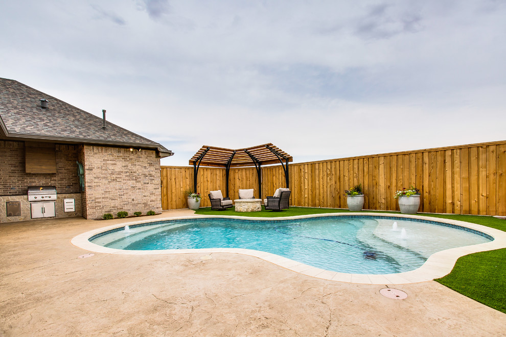 Ejemplo de piscina con fuente tradicional grande a medida en patio trasero con adoquines de hormigón