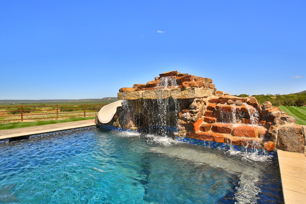 Geräumiger Klassischer Infinity-Pool hinter dem Haus in rechteckiger Form mit Wasserrutsche und Stempelbeton in Dallas