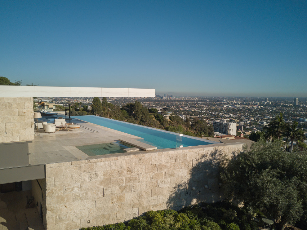 Ispirazione per una piscina a sfioro infinito minimalista rettangolare sul tetto con pavimentazioni in pietra naturale