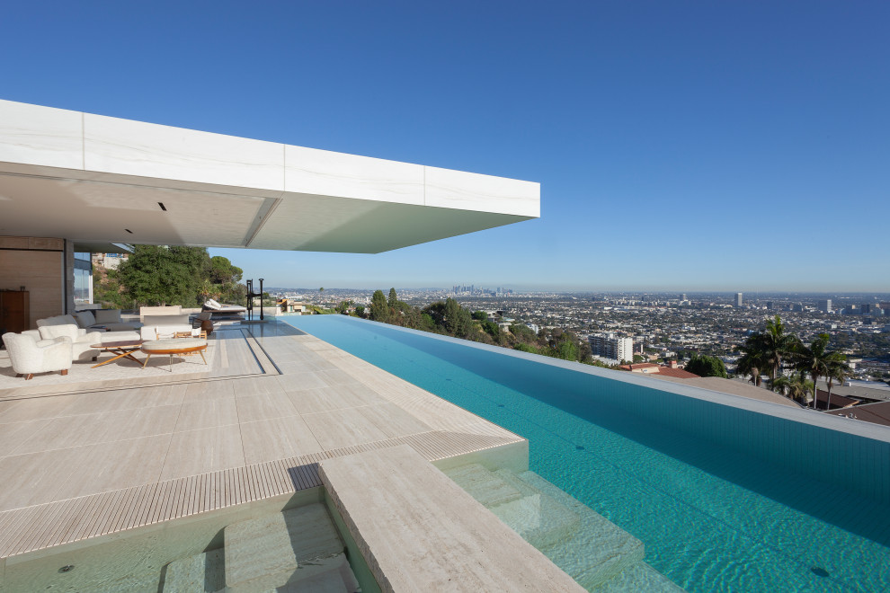 Cette image montre une piscine sur toit à débordement minimaliste rectangle avec des pavés en pierre naturelle.