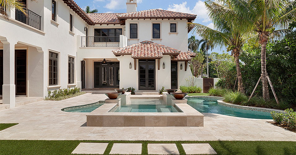 Expansive back custom shaped swimming pool in Miami with natural stone paving.